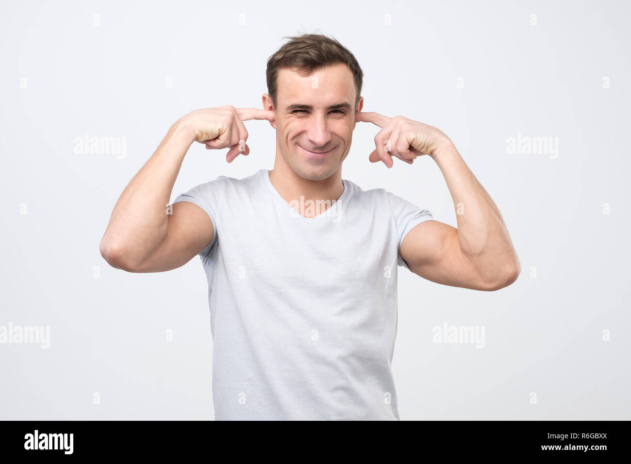 Annoyed mature italian man plugging ears with fingers Stock Photo