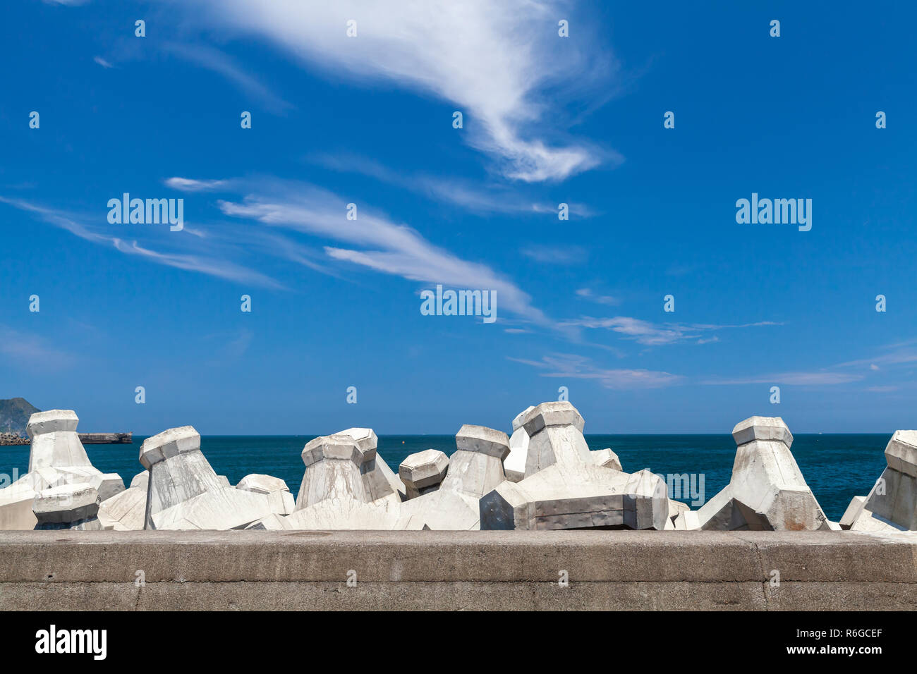 Breakwater structure with concrete blocks under cloudy sky. Industrial background photo Stock Photo