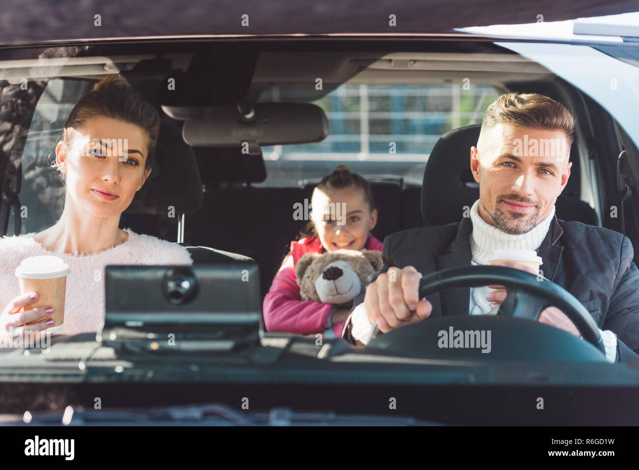 Mom and dad sitting in car with daughter and holding paper cups Stock ...