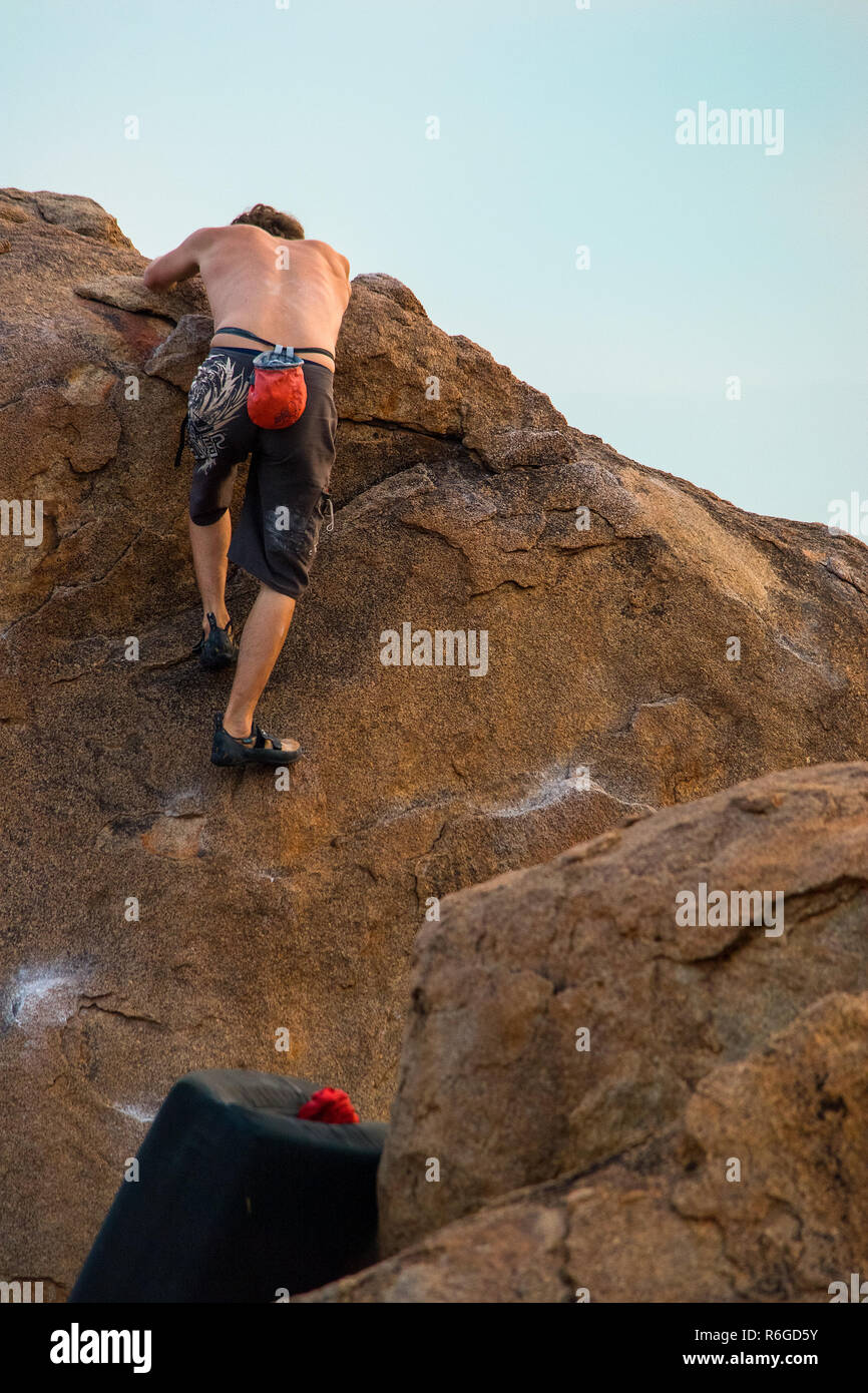 A male rock climber practices his skills, grip and strength climbing a