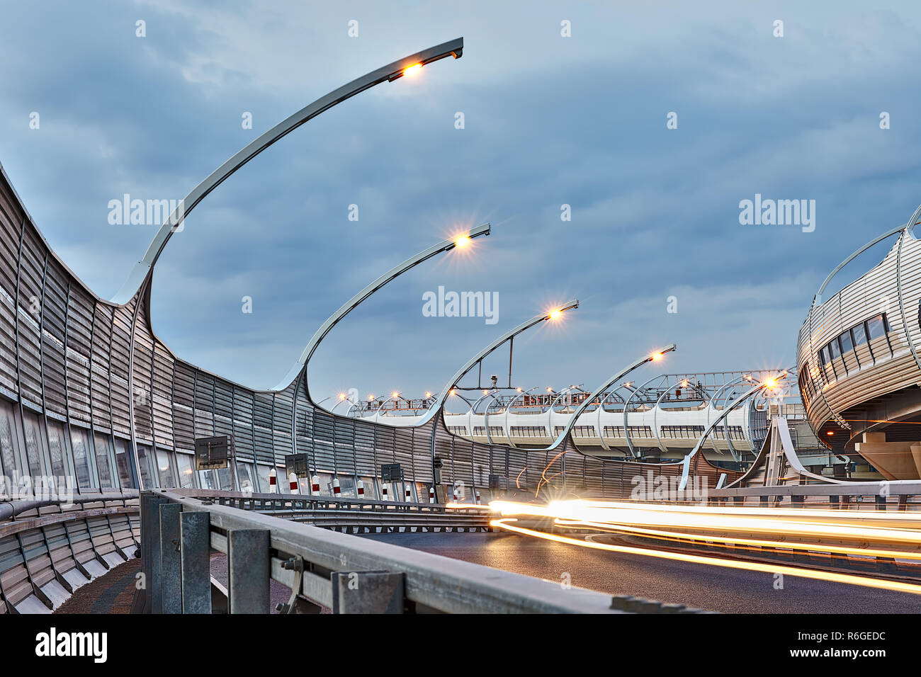 St. Petersburg, Russia - August 24, 2018: Street lighting on expressway with highway sound proof barrier panel and safety barrier fence in twilight in Stock Photo