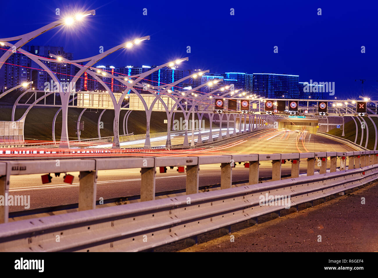 Saint Petersburg, Russia - August 24, 2018: Illuminated highway of St. Petersburg with close up of road safety barrier and  street lighting at night. Stock Photo