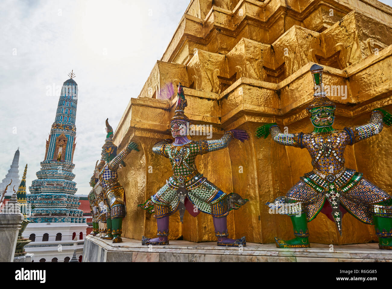 Golden Yaksha statues surrounding a pagoda in the Grand Palace in Bangkok, Thailand. The demon-gods statues are a common sight in Buddhist temples in  Stock Photo