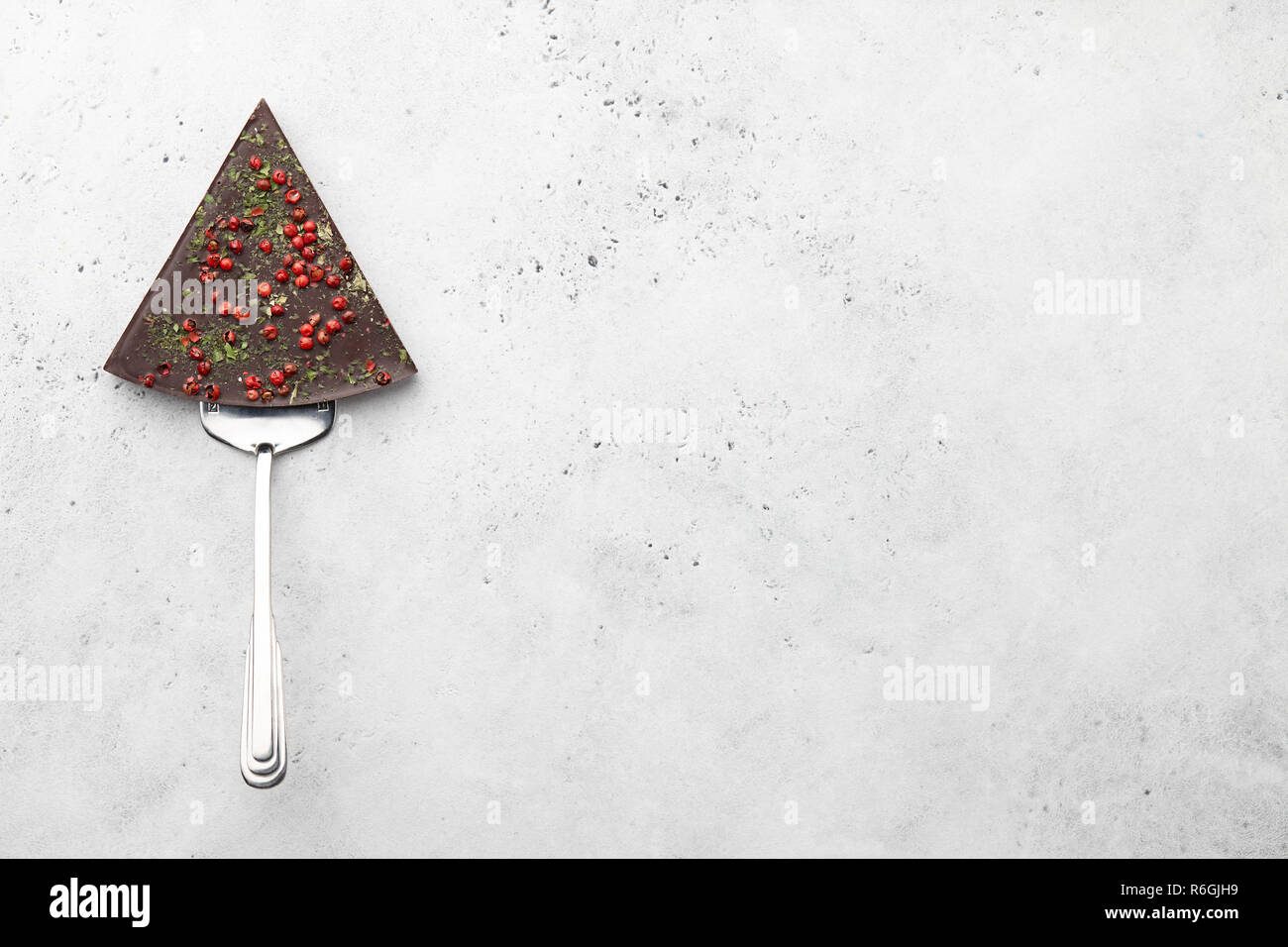 Triangle chocolate piece on spatula on stone background Stock Photo