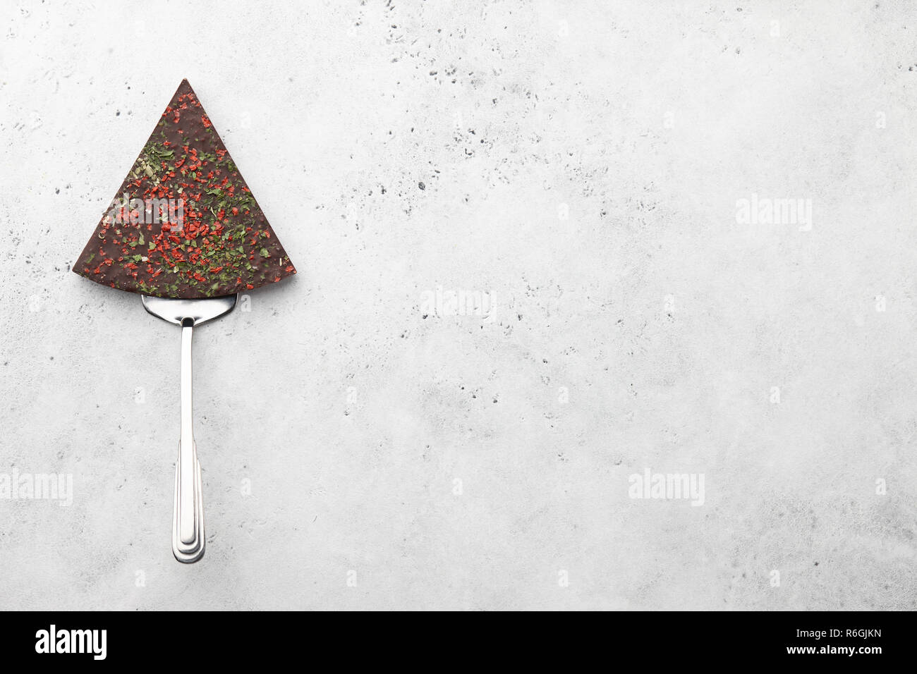 Triangle chocolate piece on spatula on stone background Stock Photo