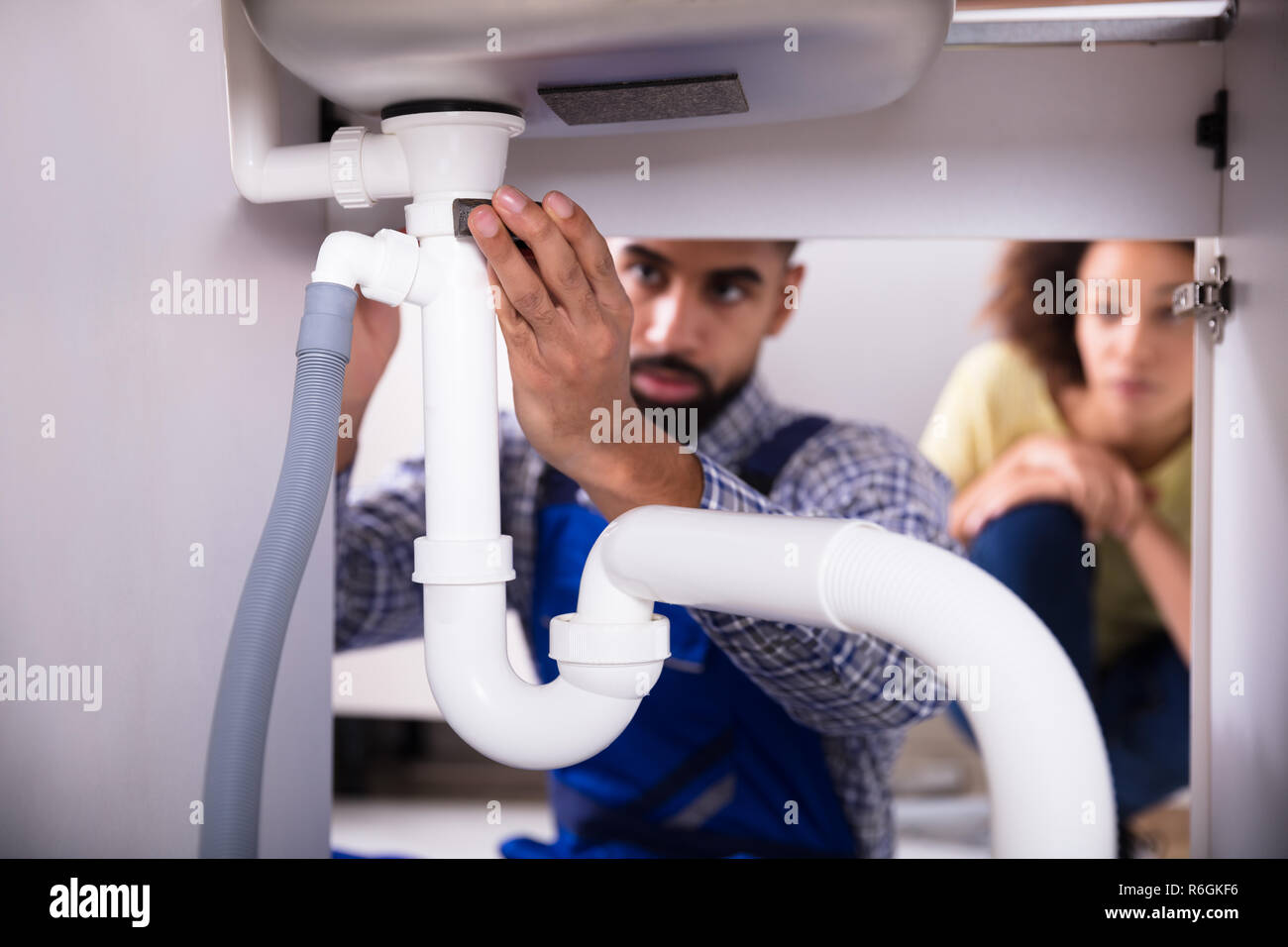 Woman fixing plumbing under sink hires stock photography and images