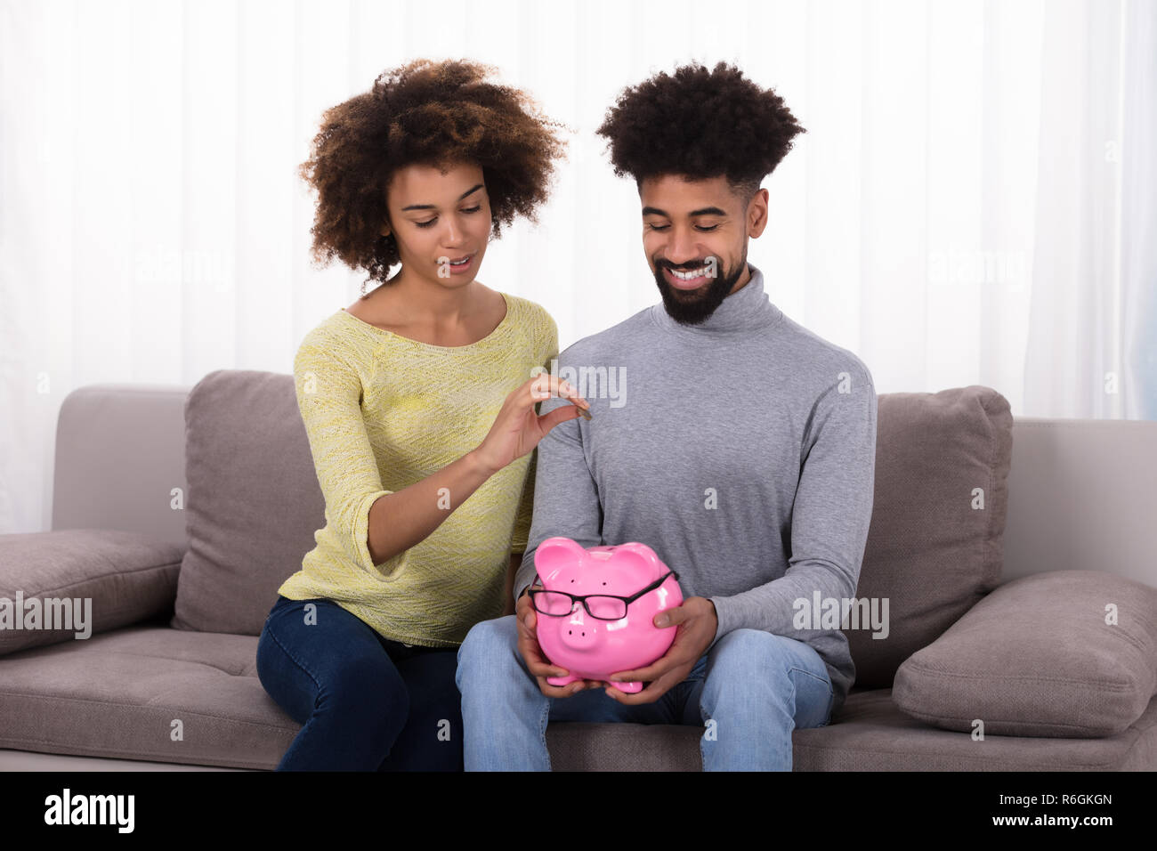 Couple Inserting Coin In Piggybank Stock Photo - Alamy