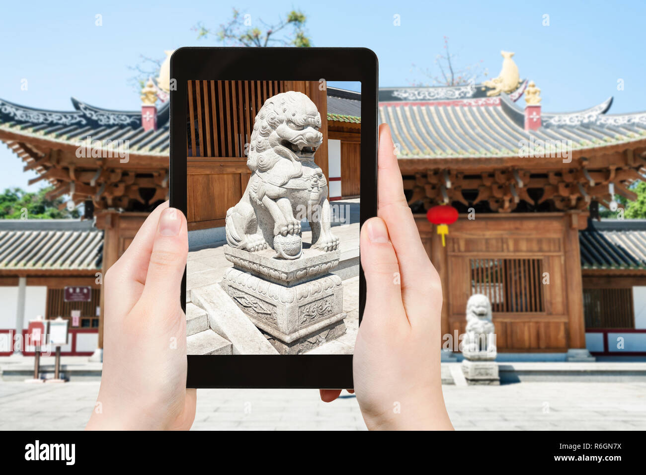 tourist photographs lion statue near temple Stock Photo