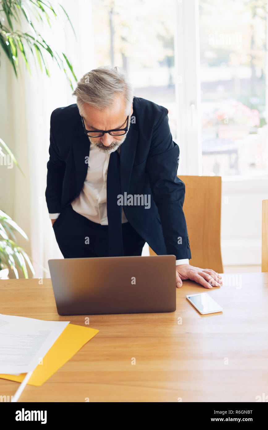Businessman Standing Up Leaning Over A Laptop Computer With His