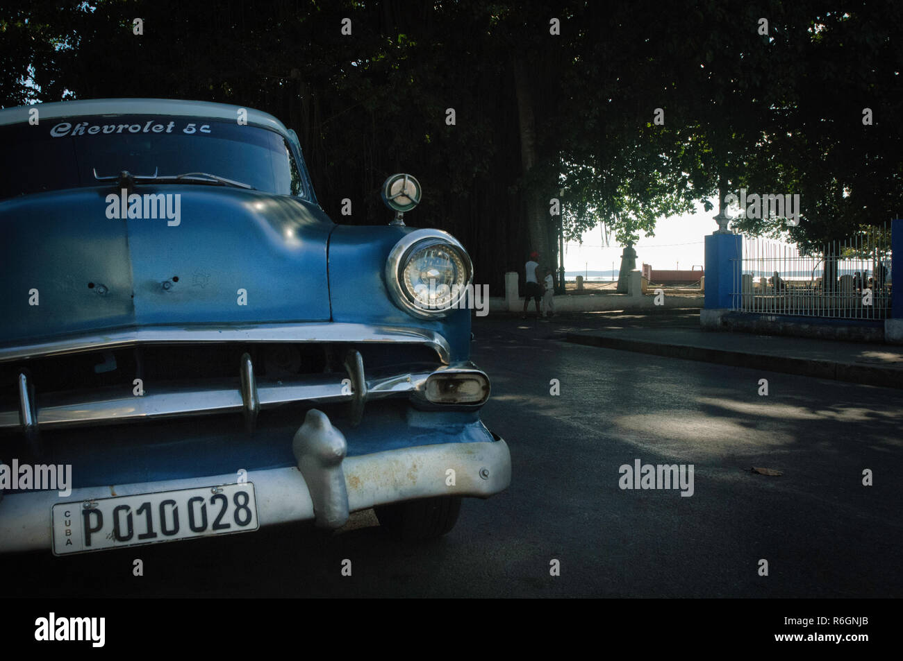 Classic chevrolet parked in the shadow under a tree near the beach at Cienfuegos, Cuba. Stock Photo