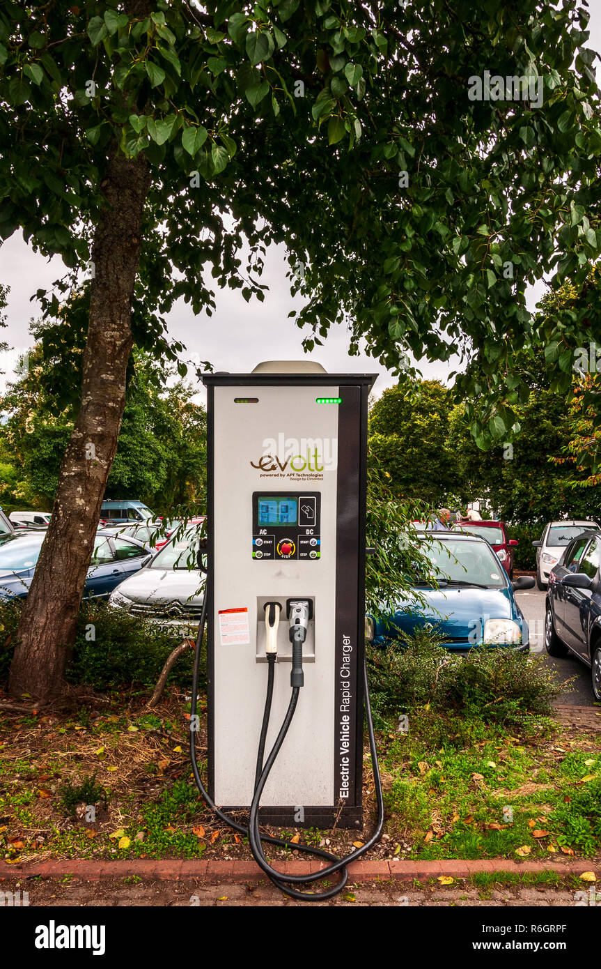 A tall rectangular painted electric vehicle rapid charger fitted with two different connectors and intuitive manual controls situated in a public car Stock Photo