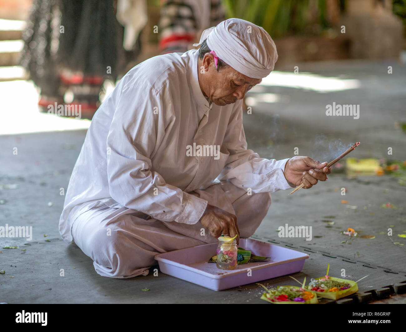 Balinese man performing a morning offering ritual in an old Hindu temple. Stock Photo