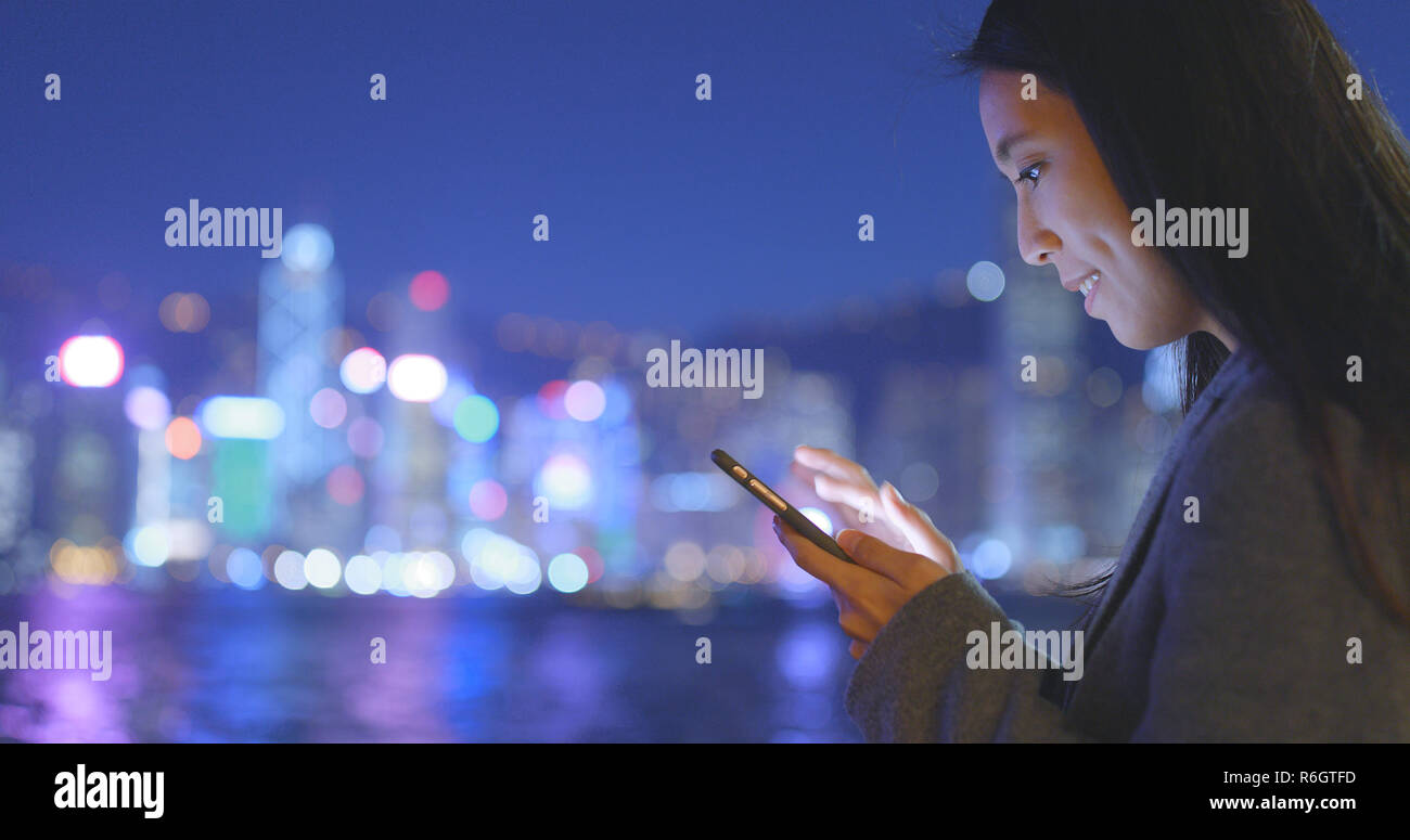 Businesswoman use of mobile phone in Hong Kong at night Stock Photo - Alamy