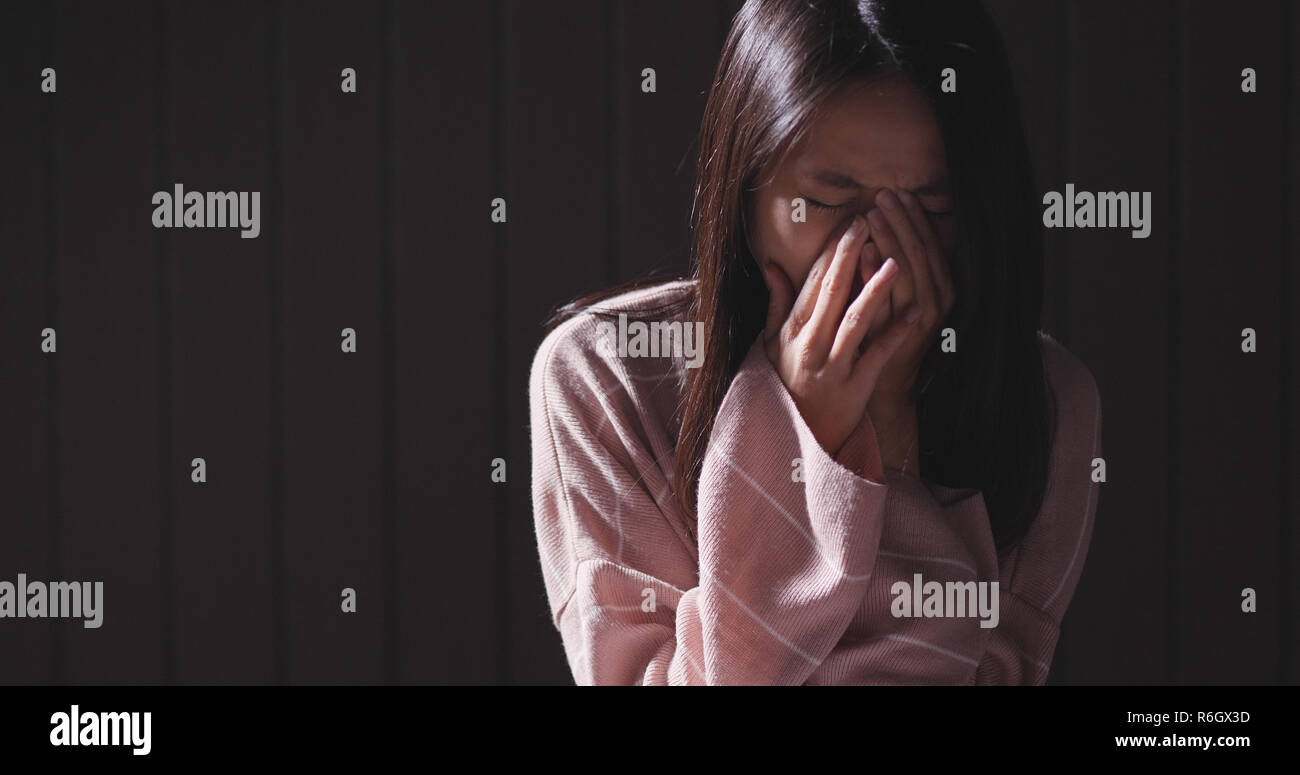 Depressed woman crying alone in the dark Stock Photo
