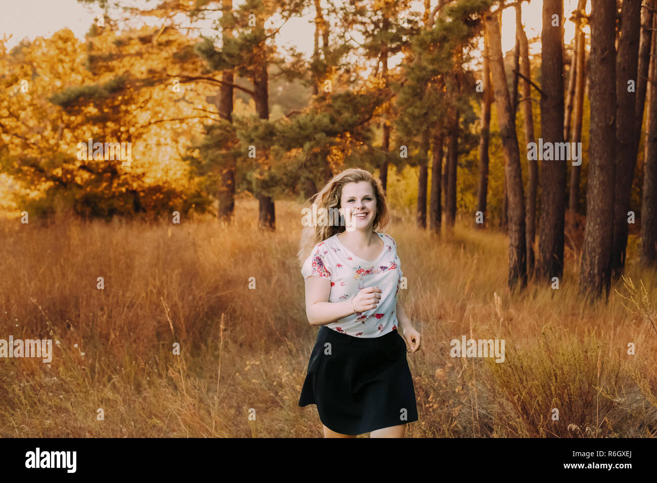 Single Young Pretty Plus Size Caucasian Happy Girl Woman In White T-Shirt Running In Autumn Forest. Enjoy Outdoor Fall Nature. Stock Photo