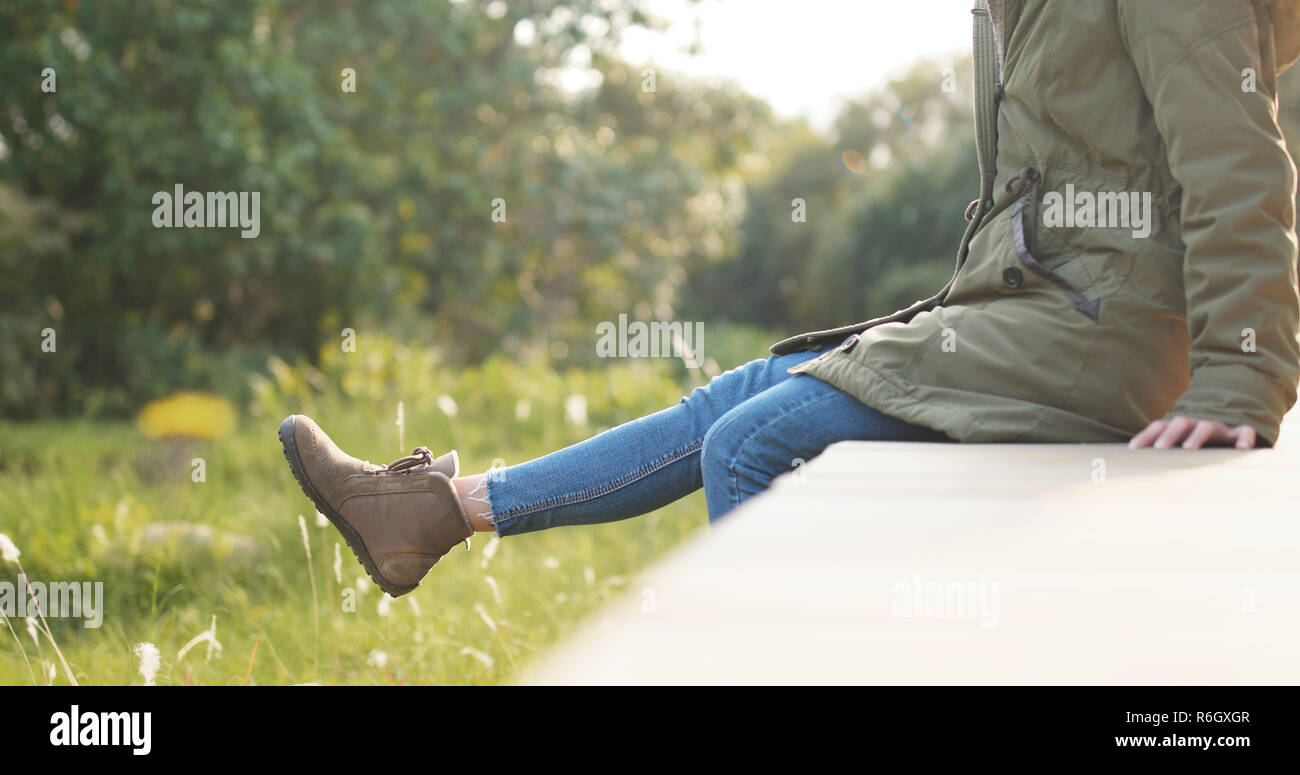 Woman sitting on the edge of a wooden jetty and swing the legs Woman ...