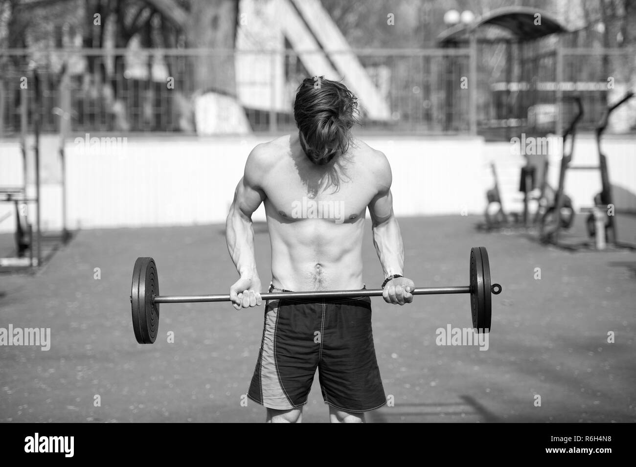 One more time. Man athlete training outdoor with barbell. Athletic man