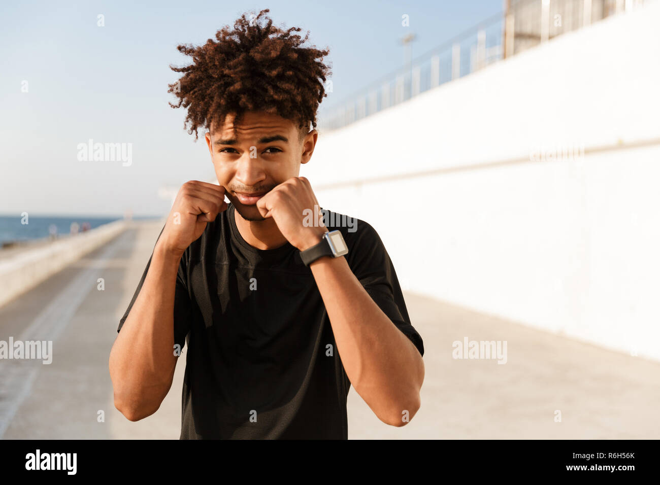 Close up of a concentrated young african sportsman standing at the beach, boxing Stock Photo