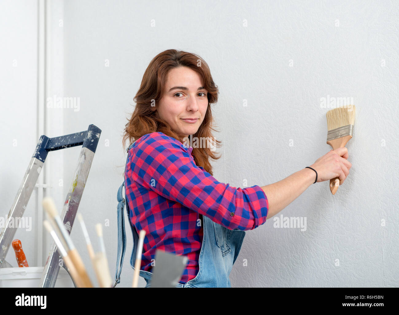 pretty young woman painting wall white color Stock Photo - Alamy
