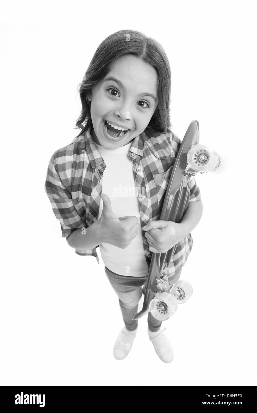 Good choice. Kid girl happy holds penny board. Child likes plastic skateboard shows thumb up. Modern teen hobby. Girl happy face carries penny board white background. Learning how to ride penny board. Stock Photo