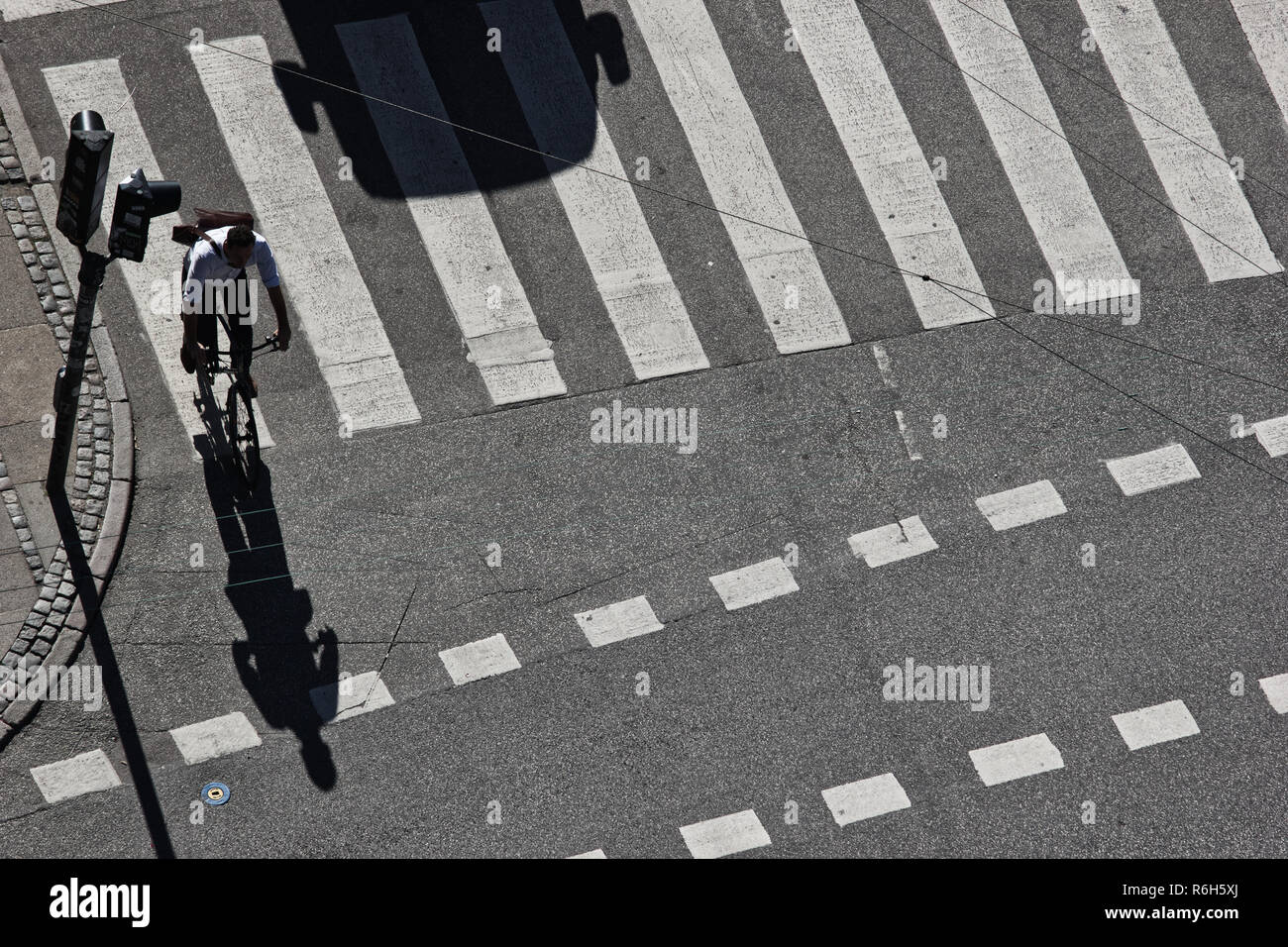 High angle shot of cyclist and shadow shape of car at pedestrian crossing, Copenhagen, Denmark, Scandinavia Stock Photo