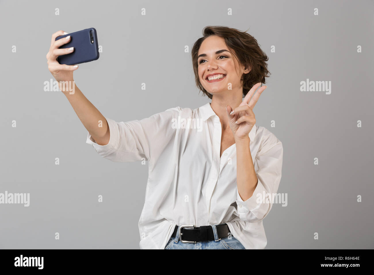 Photo of a happy young woman posing isolated over grey background make ...