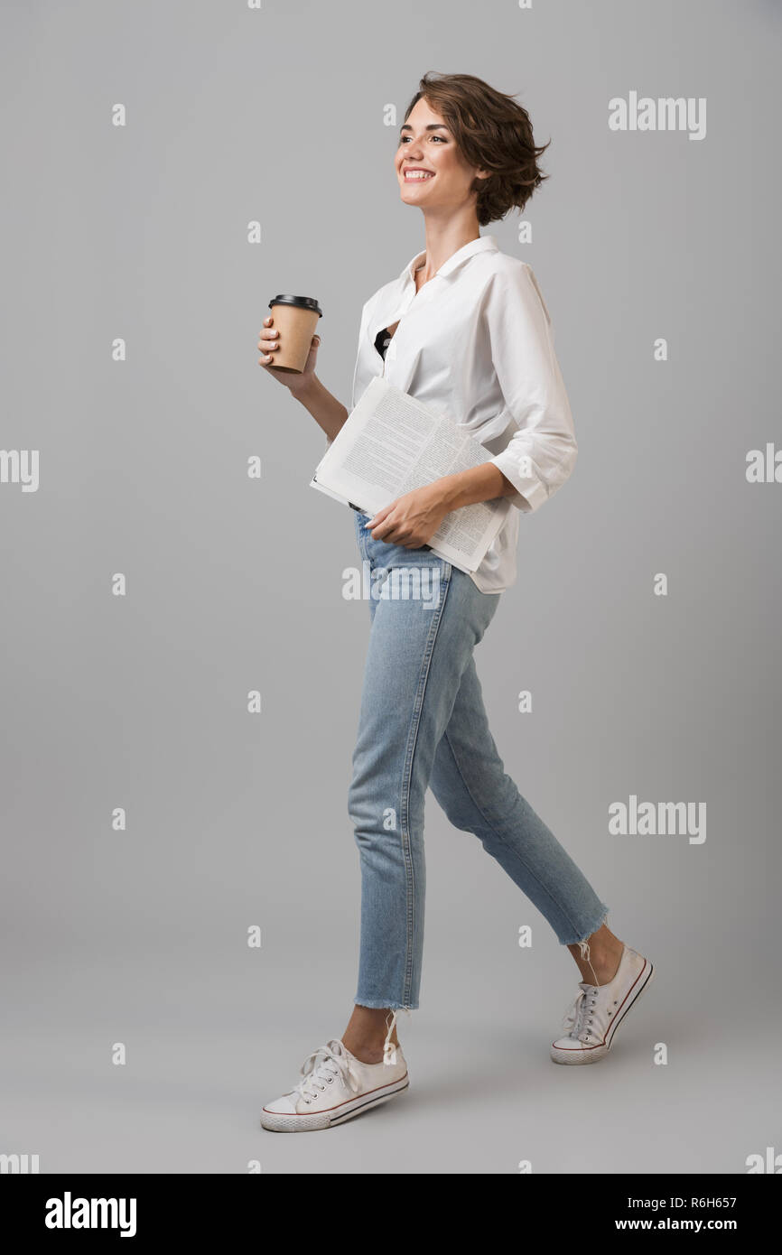 Photo Of A Happy Young Woman Posing Isolated Over Grey Background Drinking Coffee Holding Newspaper Stock Photo Alamy Photo Of A Happy Young Woman Posing Isolated Over Grey Background Drinking Coffee Holding Newspaper Stock Photo Alamy