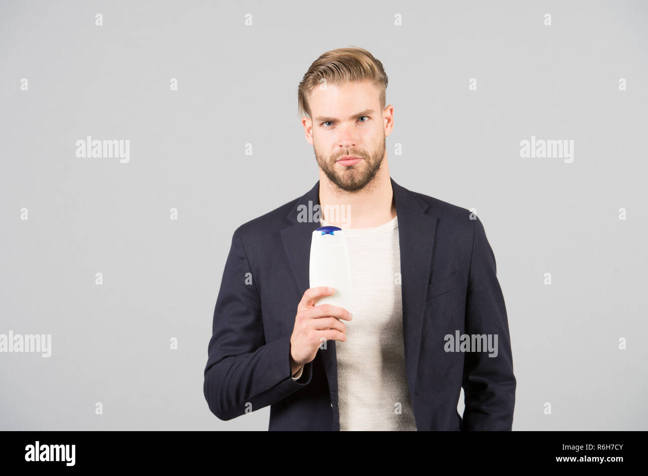 Dandruff common male problem. Remedies get rid of dandruff. Man formal suit hold bottle shampoo grey background. Itchy scalp and flakiness skin. Shampoo solve dandruff problem. Anti dandruff shampoo. Stock Photo