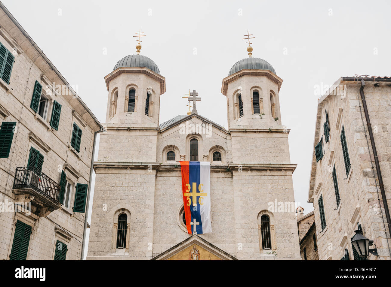View of the Orthodox Church in Kotor in Montenegro. On the building is a religious Christian flag with a cross. Stock Photo