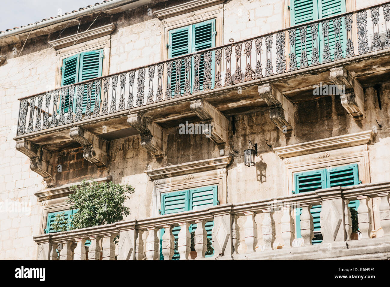 The facade of an ordinary old building with windows and balconies in Montenegro. Windows closed on the shutters. Traditional housing. Stock Photo