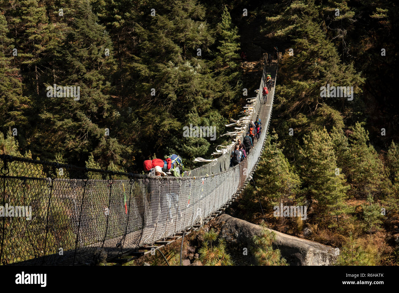 Nepal, Jorsale (Thumbug), line of people crossing metal suspension bridge over Dudh Khosi river Stock Photo