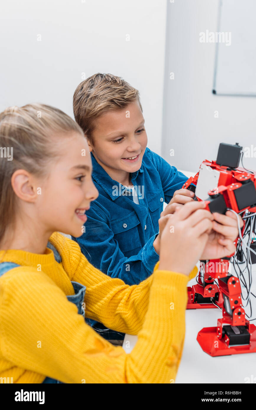 smiling schoolchildren programming robot together during STEM educational class Stock Photo