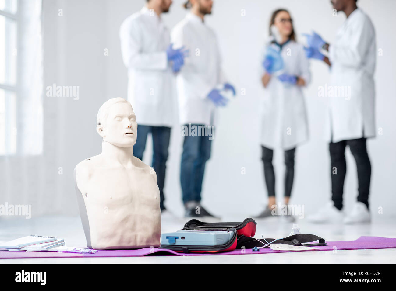 First aid medical stuff and dummies with group of young medics standing