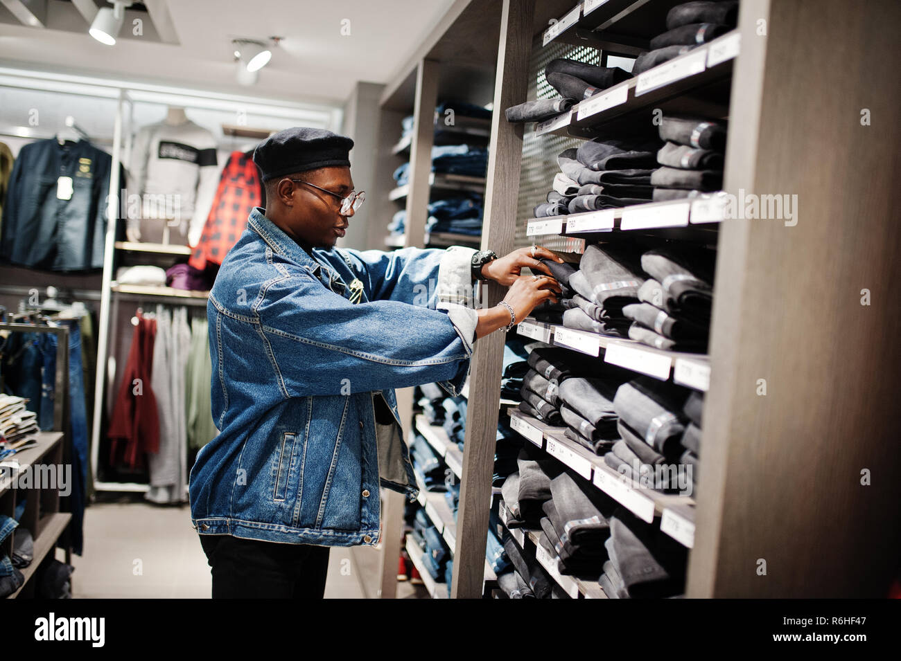 Stylish casual african american man at jeans jacket and black beret at clothes store looking on pants at shelves Stock Photo Alamy