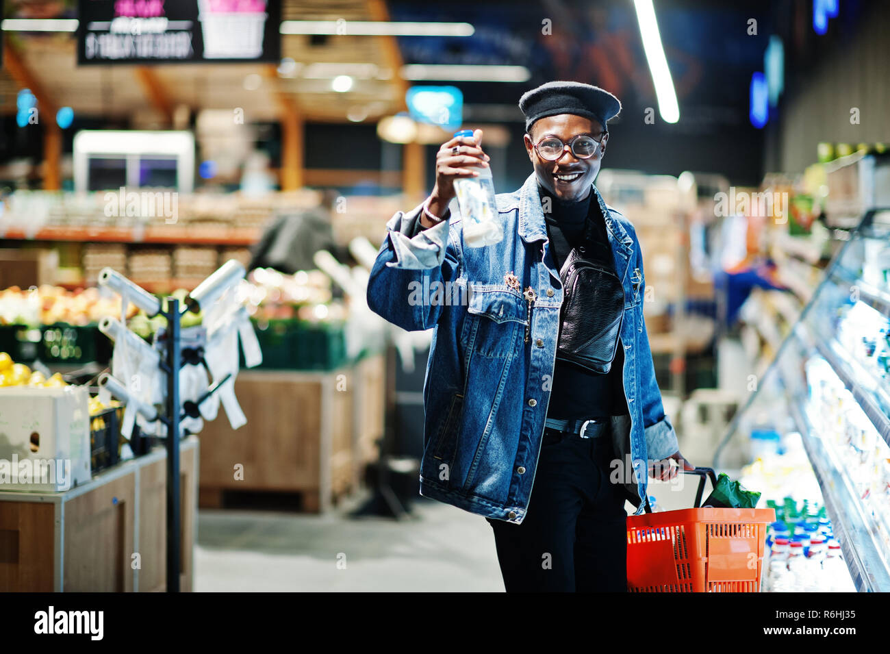 Stylish casual african american man at jeans jacket and black beret holding  basket and milk at hand, standing near fridge and shopping at supermarket  Stock Photo - Alamy