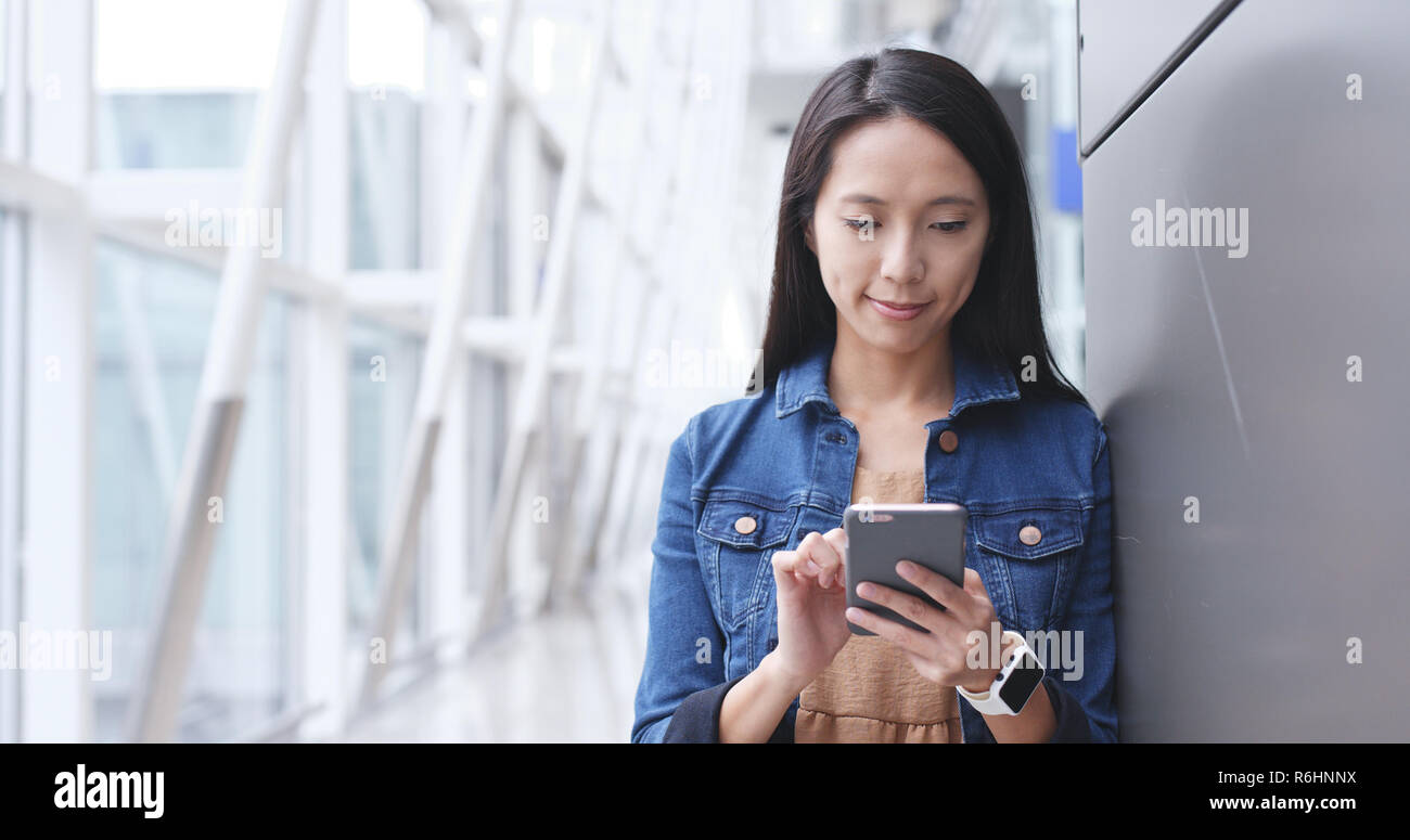Woman looking at cellphone in Hong Kong airport Stock Photo - Alamy