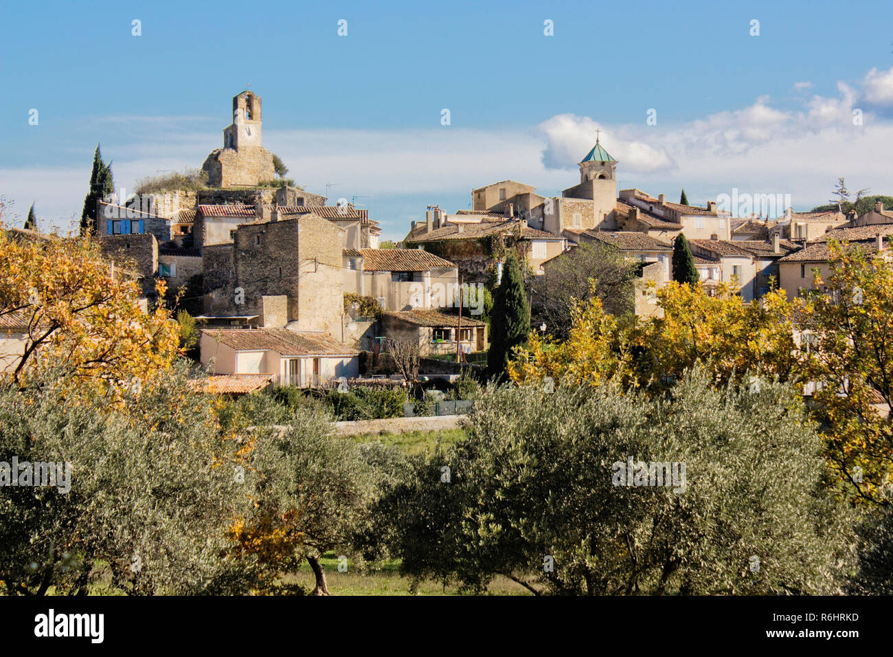 View of an old village in the Luberon region, southern France. Old church and houses with trees and sunshine. Stock Photo