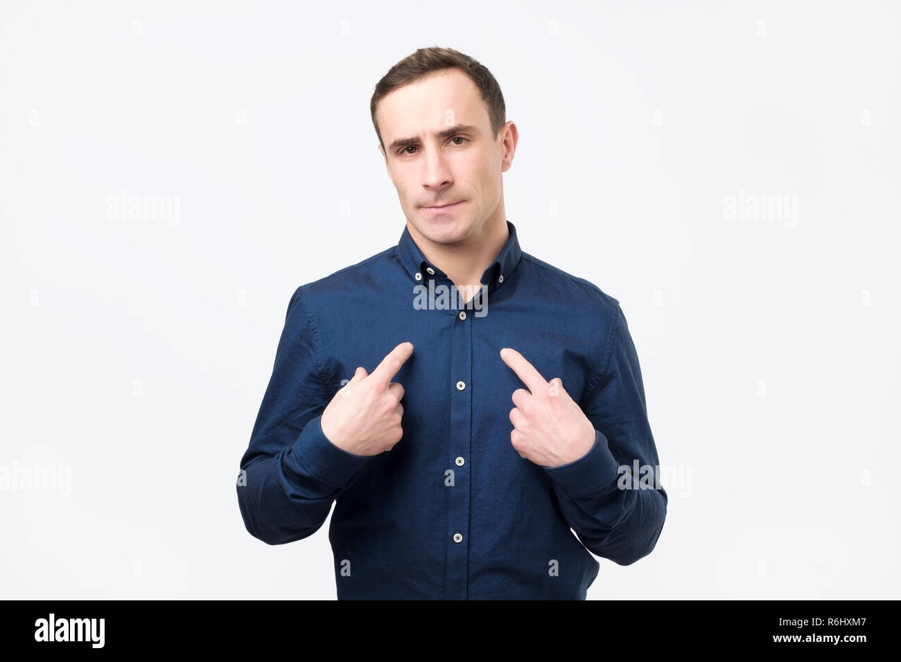 Young european man in suit pointing at himself, making excuses or verbally defending Stock Photo