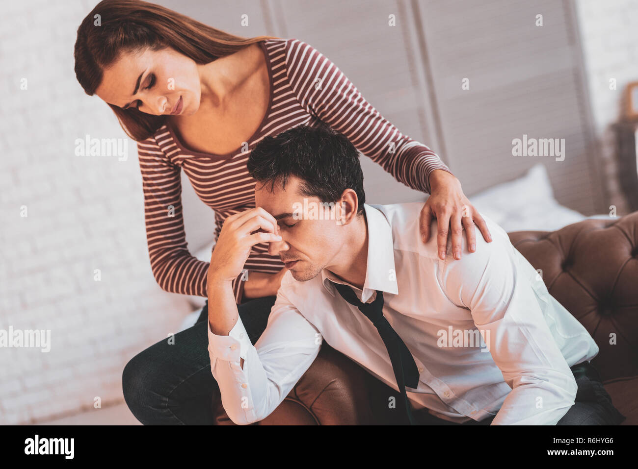 Depressed man closing his eyes and a wife sitting near Stock Photo