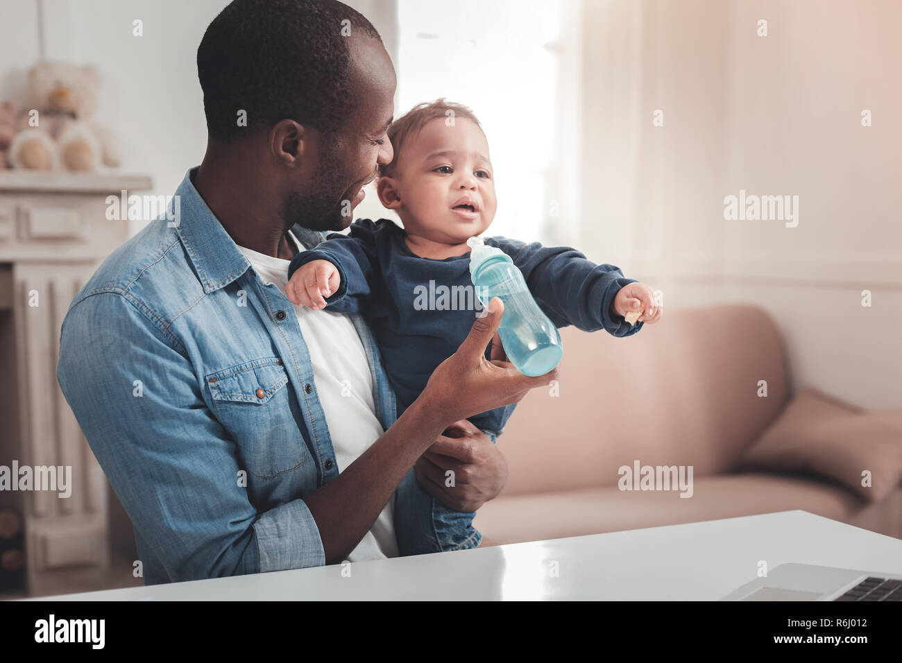 Cheerful pleasant man looking after his baby Stock Photo