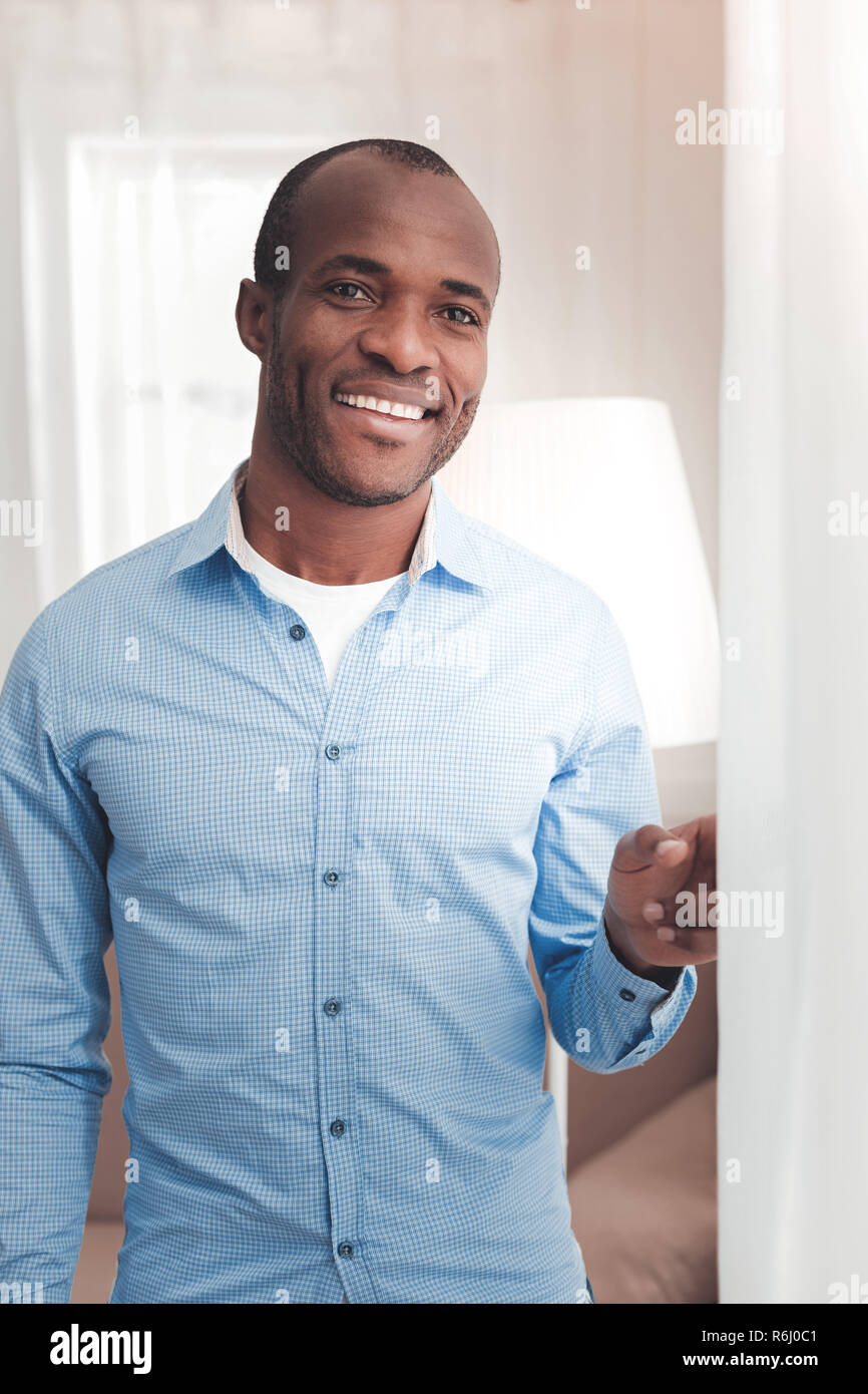 Delighted nice man standing near the curtain Stock Photo