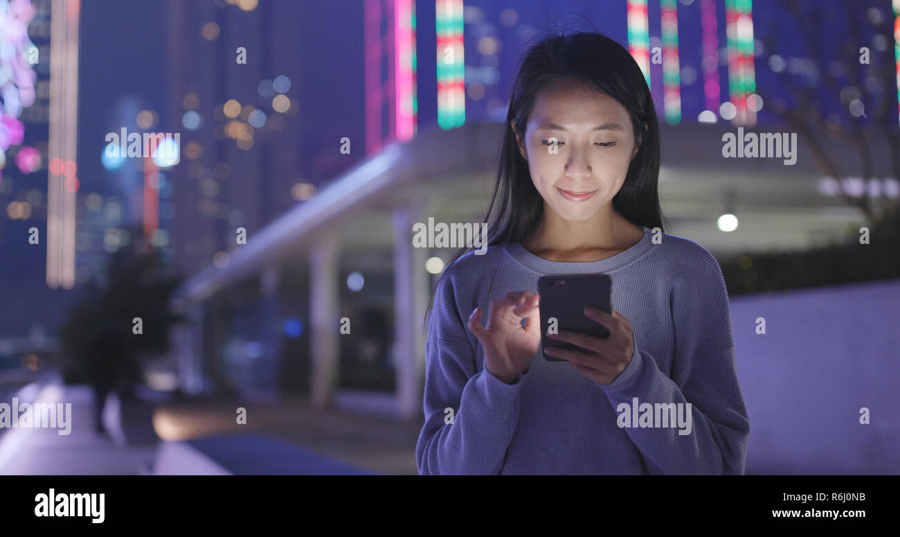 Woman look at smart phone in the city at night Stock Photo - Alamy