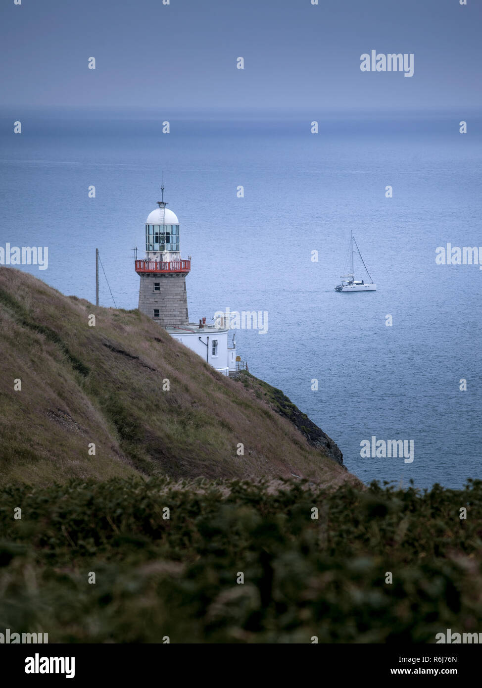Irish lighthouse partially covered by meadows on a cloudy evening, Dublin, Ireland Stock Photo