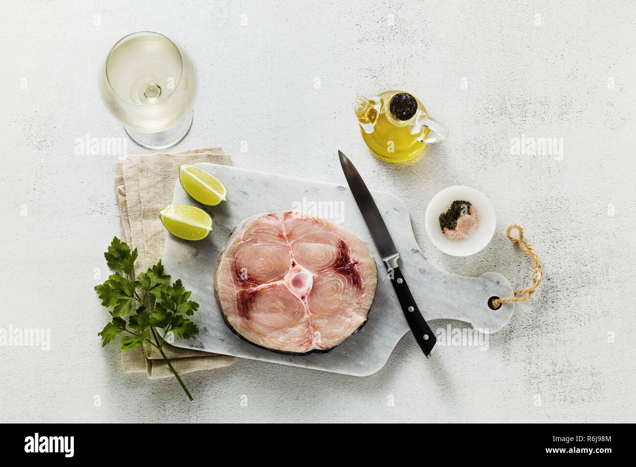 raw swordfish steak on a marble cutting board with olive oil and spices