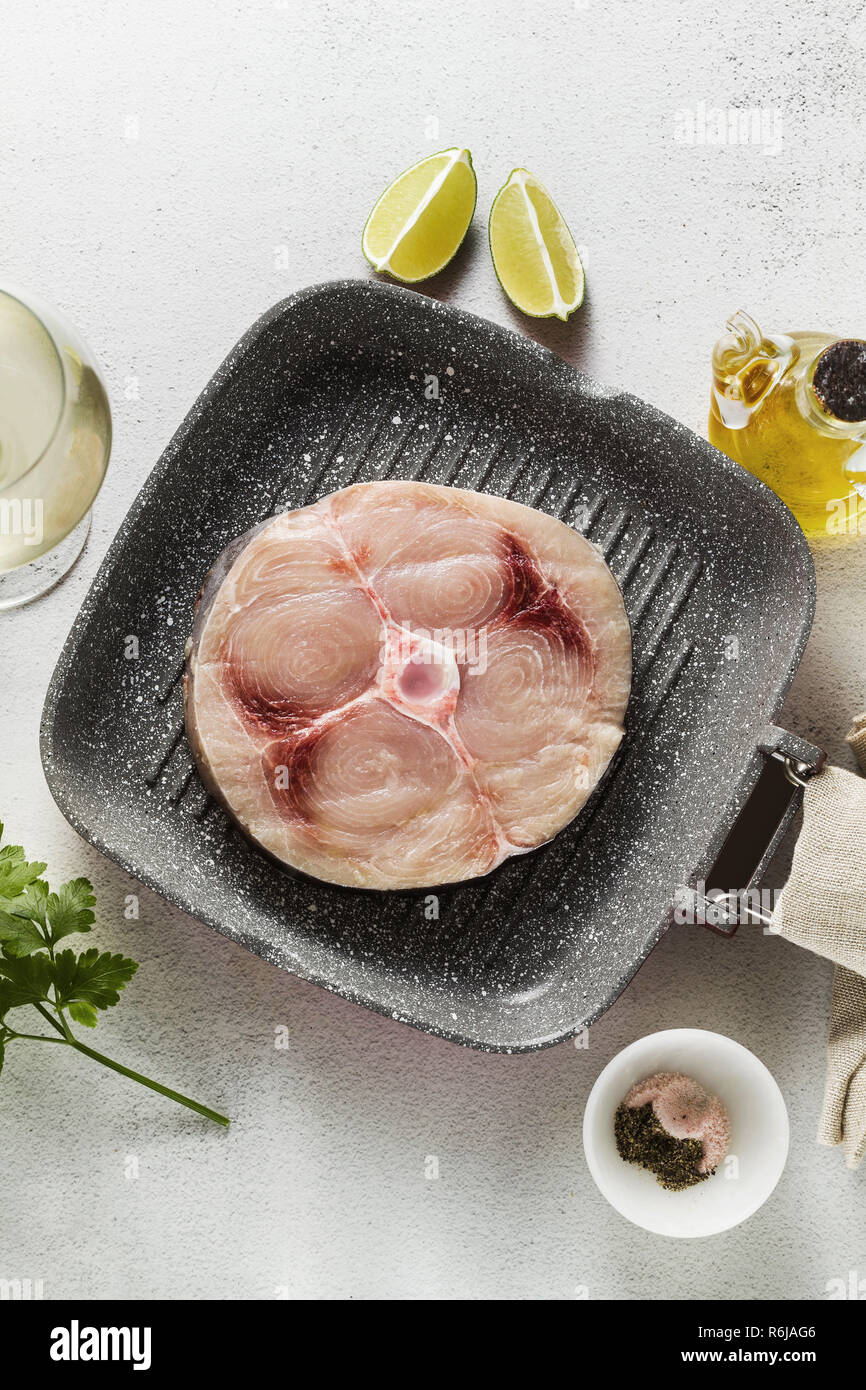 raw swordfish steak on the grill pan with olive oil and spices, white