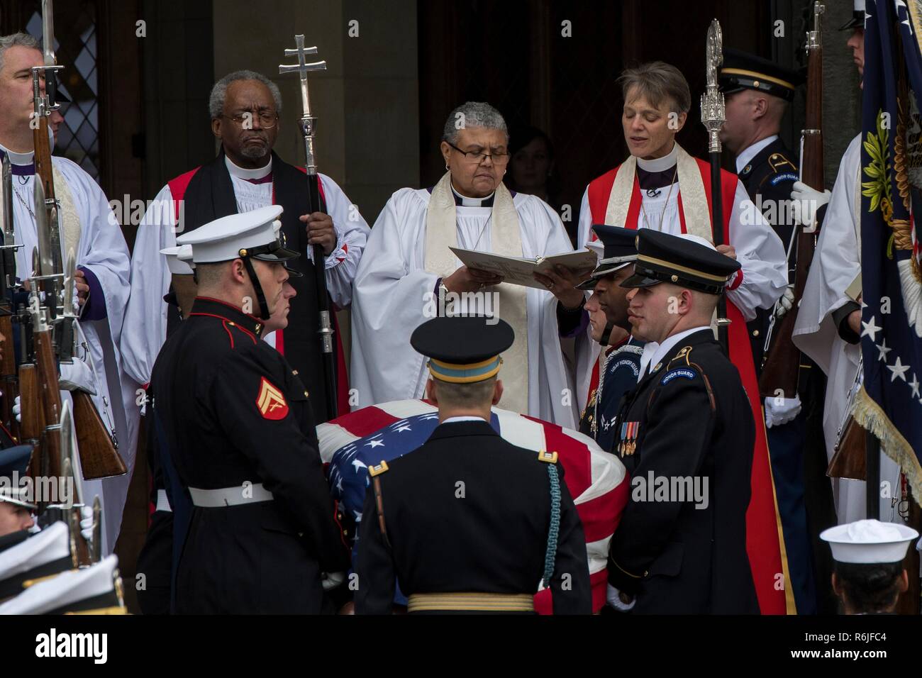 Presiding Bishop Michael Curry, left, Rev. Canon Rosemarie Logan Duncan, center, and Bishop Mariann Edgar Budde receive the flag-draped casket of former president George H.W. Bush as it arrives for the State Funeral at at the National Cathedral December 5, 2018 in Washington, DC. Bush, the 41st President, died in his Houston home at age 94. Stock Photo
