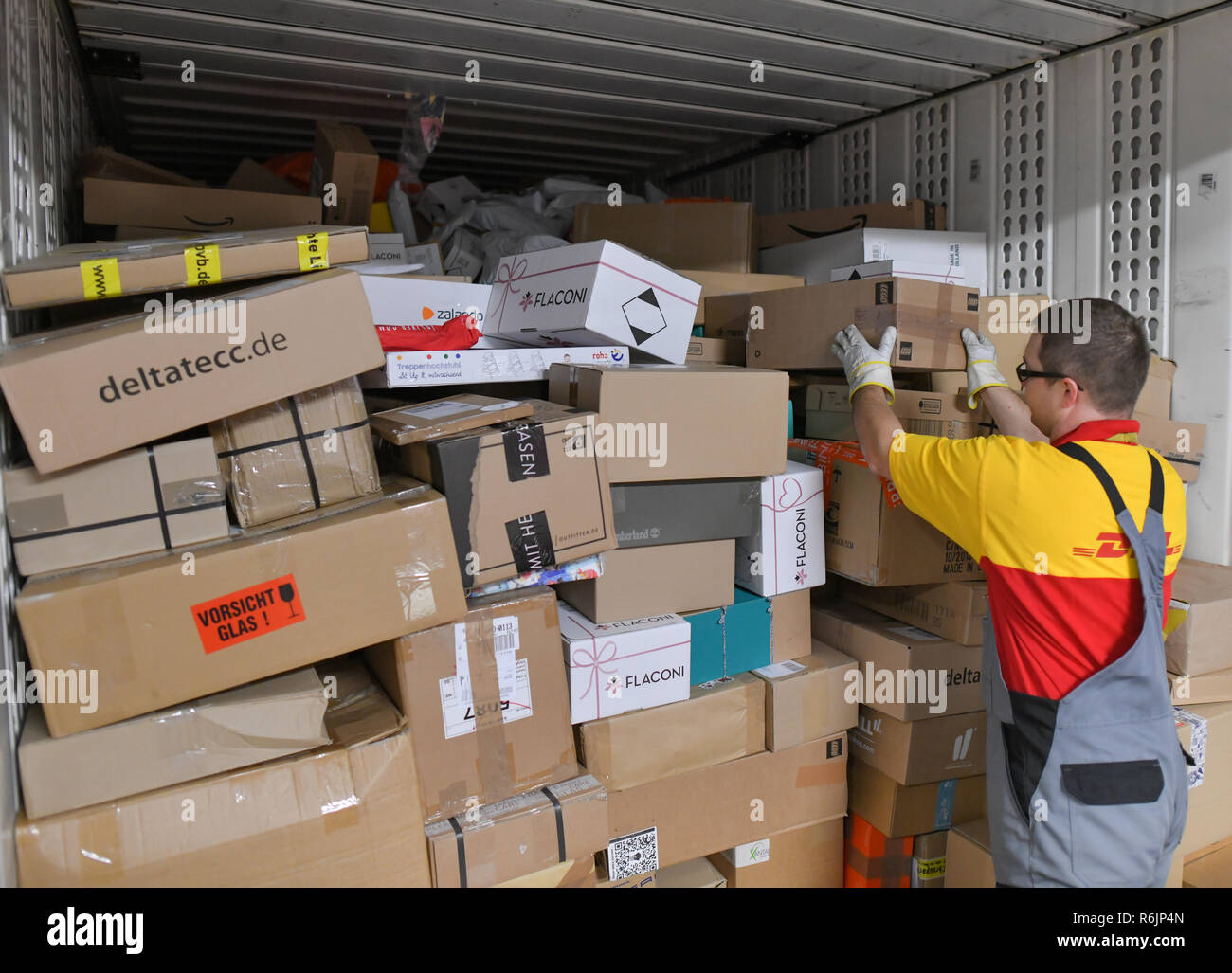 05 December 2018, Brandenburg, Rüdersdorf: Frank Hedrich, employee at DHL-Paketzentrum, stacks shipments in a truck. Let's get on with the parcels and packages: For the employees of parcel centres, it's time to roll up their sleeves again. For example at the DHL location in Rüdersdorf, Brandenburg (Märkisch-Oderland). Up to 550,000 parcels are processed here every day before Christmas. This year, the volume of consignments is again around ten percent higher than in the previous year. Photo: Patrick Pleul/dpa-Zentralbild/ZB Stock Photo