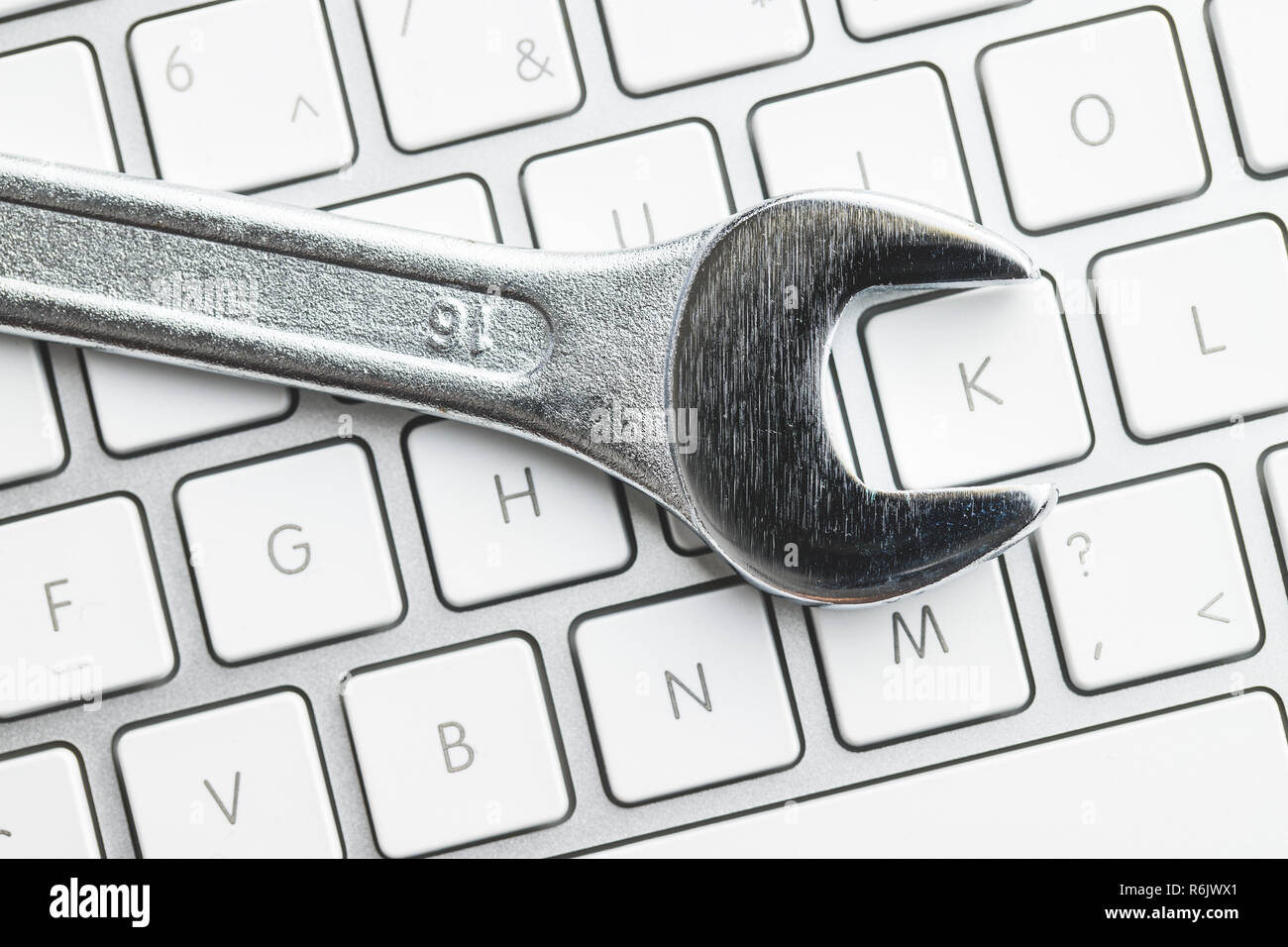 Wrench and computer keyboard. Metallic spanner on keyboard. Stock Photo