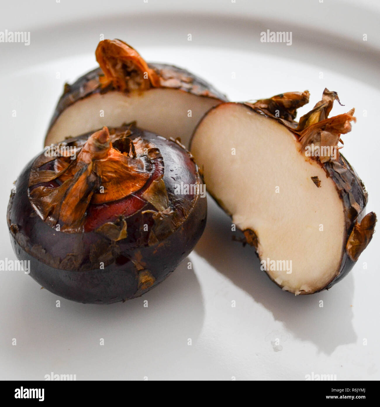 Fresh water chestnuts (Eleocharis dulcis) on a white plate, including a cross-section. Stock Photo