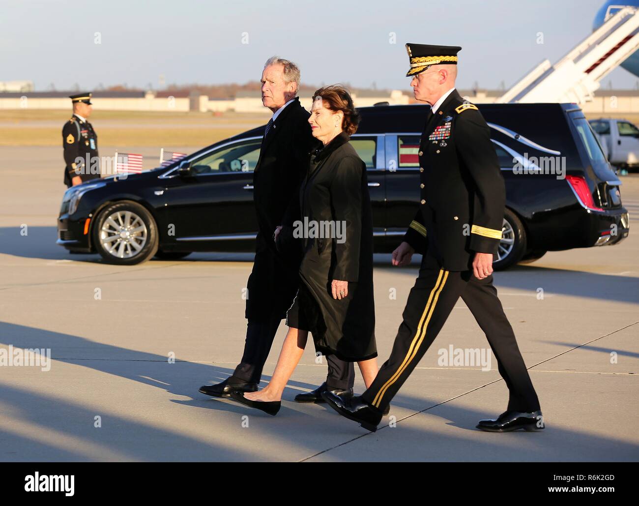 Former President George W. Bush, left, and First Lady Laura Bush, center, arrive from Houston with the the flag-draped casket of his father, former president George H.W. Bush aboard Air Force One December 3, 2018 in Andrews, Maryland. Bush, the 41st President, died in his Houston home at age 94. Stock Photo